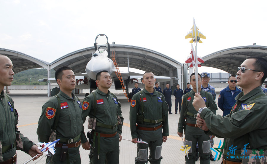 ↑艦載航空兵某部司令員戴明盟向飛行員演示空中飛行注意事項(xiàng)。
