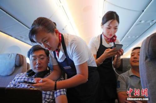 資料圖：乘務(wù)員們在客艙內(nèi)為旅客調(diào)試機上上網(wǎng)功能。<a target='_blank' ><p  align=